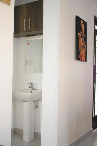 a white bathroom with a sink and a mirror at One bedroom apartment in Nairobi