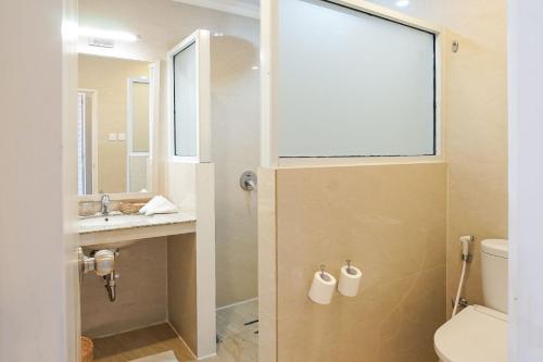 a bathroom with a toilet and a sink and a window at Hotel Villa Emitta in Tomohon