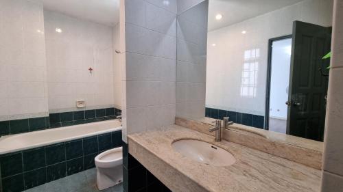 y baño con lavabo, aseo y espejo. en Kenyalang Emerald Riverine Resort Homestay, en Kuching