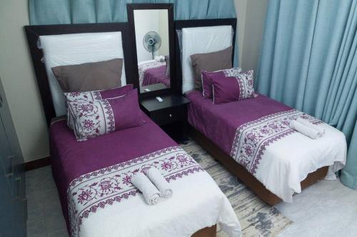 a bedroom with two beds with purple and white sheets at Netflix/WI-FI, 3 bedroom and free parking in Livingstone