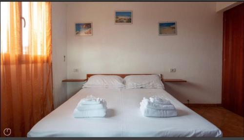 1 dormitorio con 1 cama con 2 toallas en Airport at 25 min ByWalk-Big Port 10 min by bus-Bus&CommCenter 1 min by walk - 1 min by walk to bus to city and beaches 1 min by walk to touristic port-entire Apartement with 3 indipendent rooms Air cond&WIFI&washMachine till 6 pex AZZURRO en Olbia