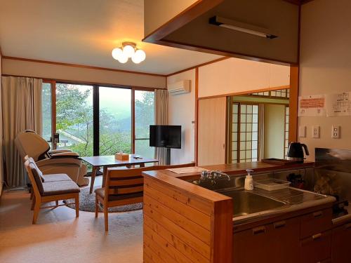 a kitchen with a sink and a living room with a table at Yufuin Hoshinosato in Yufuin