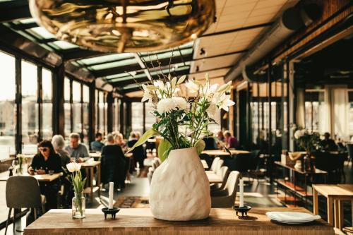 a vase of flowers on a table in a restaurant at Slottsholmen Hotell och Restaurang in Västervik