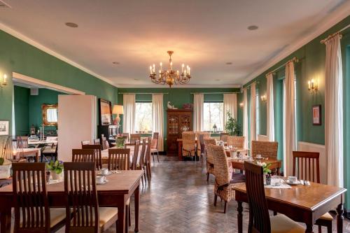 een restaurant met houten tafels en stoelen en groene muren bij Golf- & Landhotel am alten Deich in Büsum