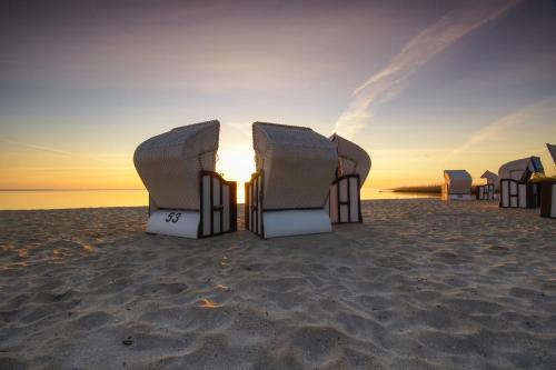 a group of beach chairs on the beach at sunset at Haff Ostseeferienhaus unteres Apartment in Mönkebude