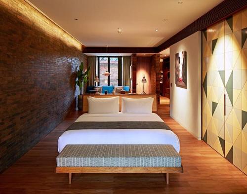 a bedroom with two beds and a brick wall at Potato Head Suites & Studios in Seminyak