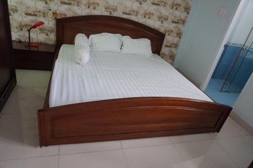 Una cama con sábanas blancas y un osito de peluche. en Helen's homestay, en Ho Chi Minh