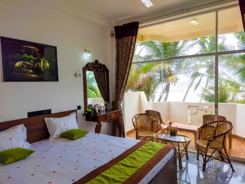 een slaapkamer met een bed en een groot raam bij Hotel Coconut Bay in Kalutara