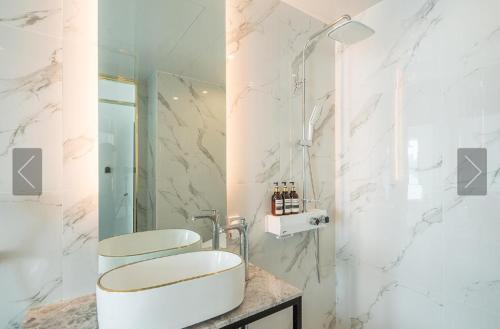a white bathroom with a sink and a mirror at De Homme Hotel in Busan