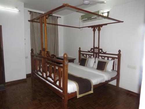 a bedroom with a wooden canopy bed in a room at Maison Petite Singapore in Pondicherry