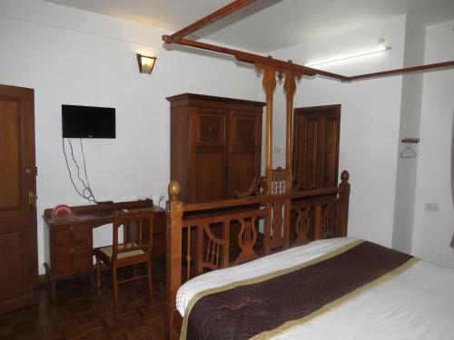 a bedroom with a wooden bed and a desk at Maison Petite Singapore in Puducherry