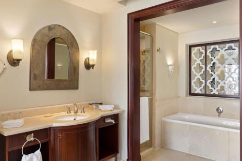 a bathroom with a sink and a tub and a mirror at Pickalbatros The Palace Port Ghalib in Port Ghalib