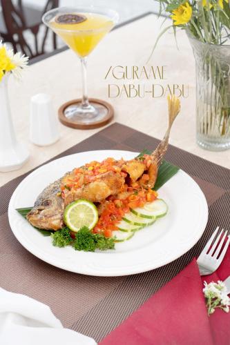 a plate of food with fish and vegetables on a table at MAHALAYA The Legacy Hotel in Solo