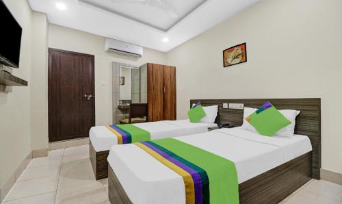 two beds in a hotel room with a television at Treebo Darwesh Residency - 500m from Railway Station in Kozhikode