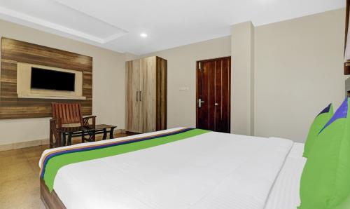 a bedroom with a bed and a chair and a television at Treebo Darwesh Residency - 500m from Railway Station in Kozhikode