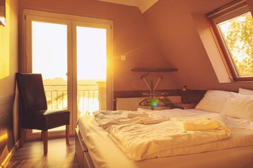 a bedroom with a bed and a chair and a window at Mártoni Villa in Szigetszentmárton