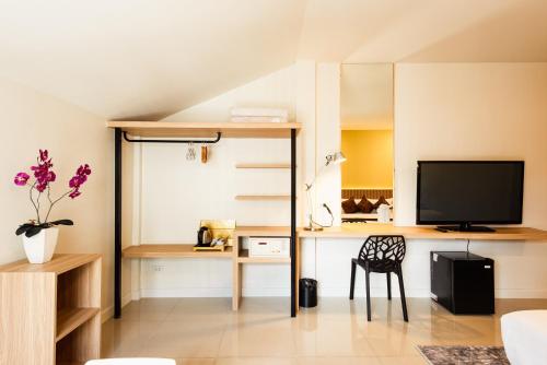 a living room with a tv and a desk at The Golden Ville Boutique Hotel and Spa in Pattaya