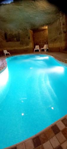 - une grande piscine bleue dans une grotte dans l'établissement Ta Majsi farmhouse with indoor heated pool, à San Lawrenz