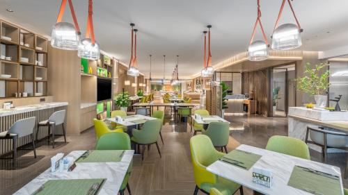 長沙市にあるHoliday Inn Changsha Malanshan, an IHG Hotelの緑の椅子とテーブルのあるレストラン、バー