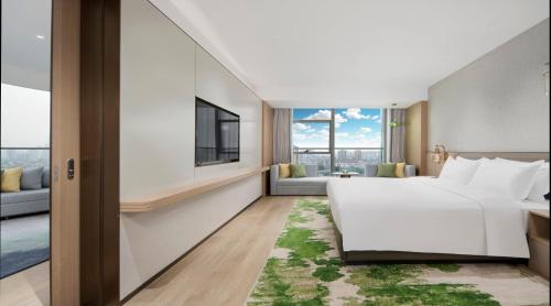 a bedroom with a large white bed and a living room at Holiday Inn Changsha Malanshan by IHG in Changsha