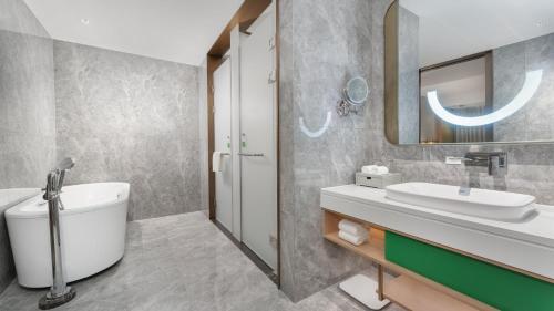 a bathroom with a sink and a toilet and a mirror at Holiday Inn Changsha Malanshan by IHG in Changsha