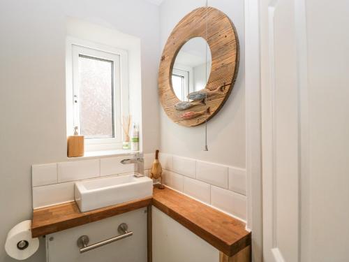 a bathroom with a sink and a mirror at Curlew Cottage in Lymington