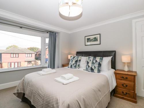 a bedroom with a bed and a large window at Curlew Cottage in Lymington