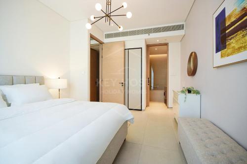 ein Schlafzimmer mit einem großen weißen Bett und einer Bank in der Unterkunft KeyHost - Exquisite 1BR - The Address Beach Residences JBR - K350 in Dubai