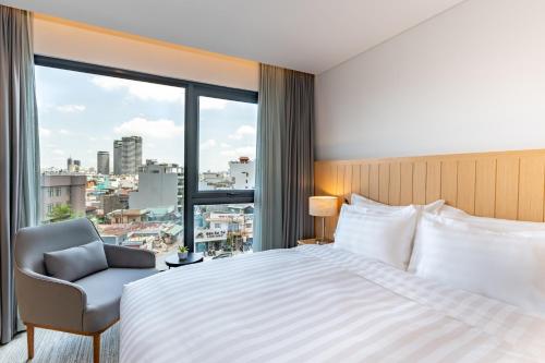 um quarto com uma cama e uma cadeira e uma grande janela em Hello World Saigon em Ho Chi Minh
