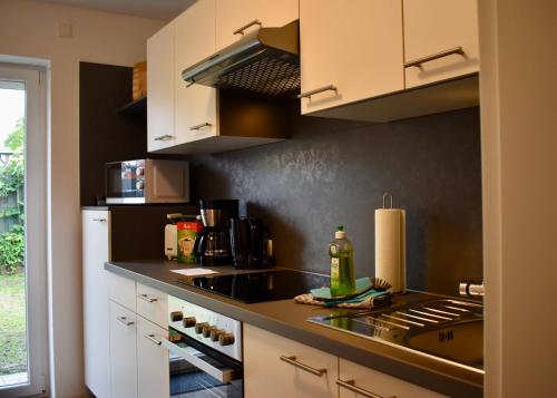 uma cozinha com armários brancos e um balcão preto em Kontorhaus Senftenberg em Senftenberg