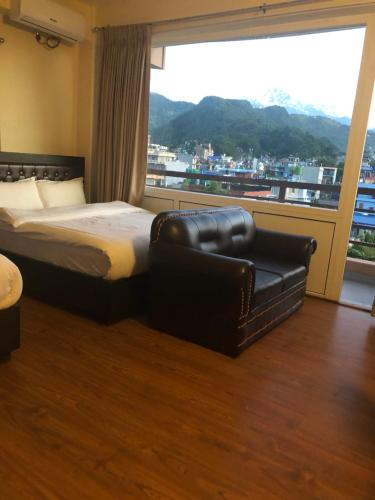 a bedroom with a bed and a chair in front of a window at Hotel Lilyland Pvt Ltd in Pokhara