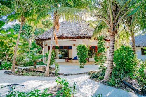 a house with palm trees in front of it at Spice Island Hotel & Resort in Jambiani