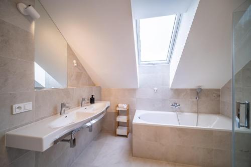 La salle de bains est pourvue de 2 lavabos, d'une baignoire et d'une fenêtre. dans l'établissement Holiday House U Hájenky 13P Lipno Home, à Lipno nad Vltavou