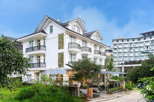 un bâtiment blanc avec balcon et un hôtel dans l'établissement Dalat Wind Hotel, à Đà Lạt