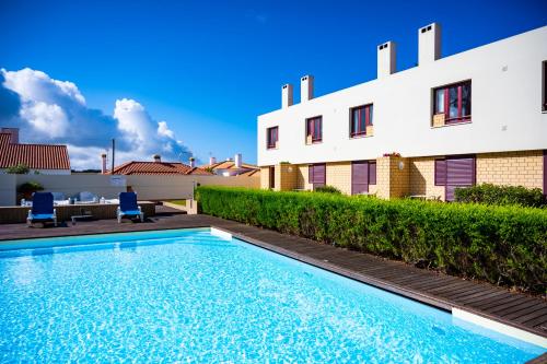 a swimming pool in front of a building at Hotel Apartamento Porto Covo in Porto Covo