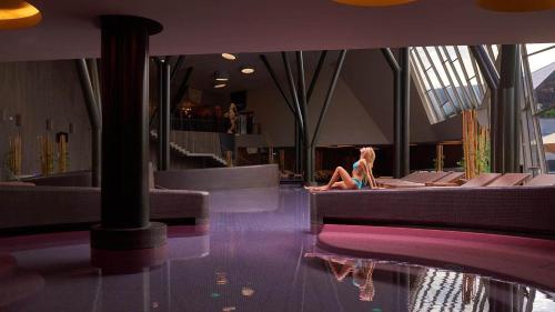a woman sitting on a couch in a building at Terme Olimia - Hotel Breza in Podčetrtek