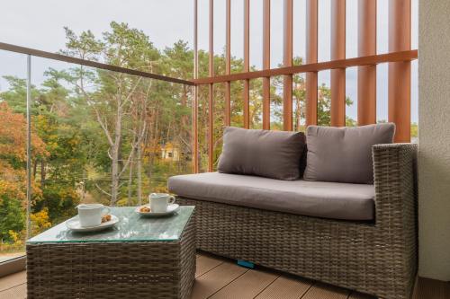 a balcony with a couch and a table and a window at Apartments Mazowiecka Pobierowo by Noclegi Renters in Pobierowo