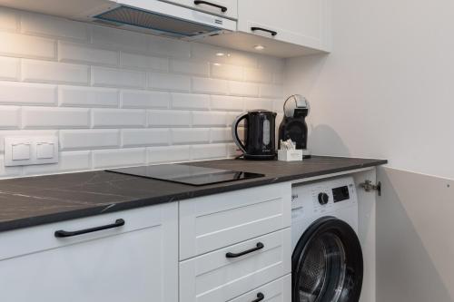 a white kitchen with a washing machine in it at Apartments Mazowiecka Pobierowo by Noclegi Renters in Pobierowo