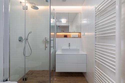 a white bathroom with a sink and a shower at Apartments Mazowiecka Pobierowo by Noclegi Renters in Pobierowo