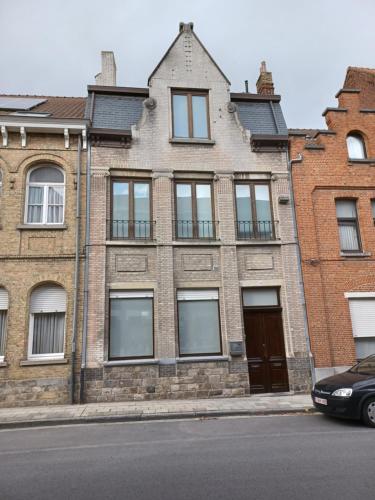 a large brick building with windows on a street at De Galerie - green leaves in Ieper