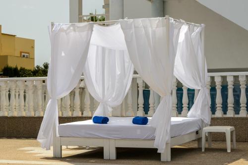 1 cama con cortinas blancas en el balcón en Hotel Apartamentos Vibra San Marino en San Antonio Bay