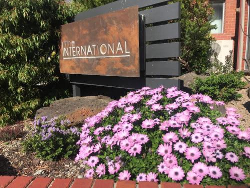 a bunch of pink flowers in front of a sign at The International Motel Apollo Bay in Apollo Bay