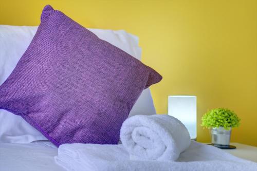 a purple pillow and towels on top of a bed at Honeysuckle Road in Sheffield