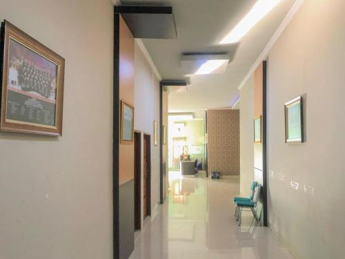 a hallway of a hospital with a chair and paintings at Edotel SMKN 2 Pinrang Mitra RedDoorz in Pinrang