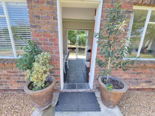two potted plants sitting on the front door of a house at Kwetu Guest Farm in Swellendam