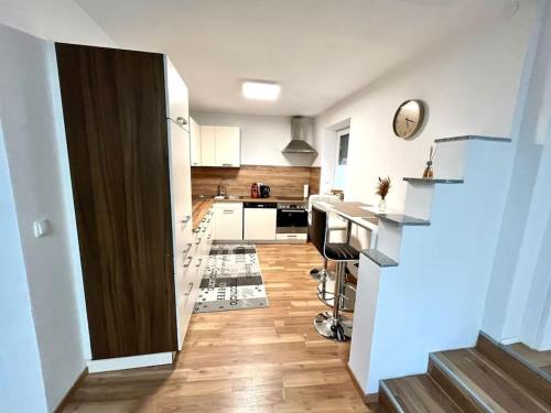 a kitchen with white cabinets and a wooden floor at AB Apartment Moderne Zweizimmerwohnung in Villach