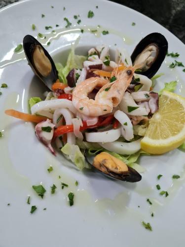 a white plate with a salad with shrimp and vegetables at Hotel Salento in Specchia
