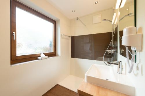 a bathroom with a sink and a window at Hotel & Gasthof Kröll in Niedernsill