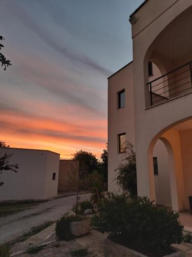 a building with a sunset in the background at Hotel Salento in Specchia