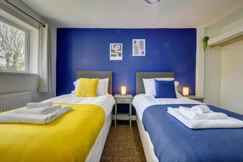 two beds in a room with blue and yellow at Thurnby Lodge in Leicester